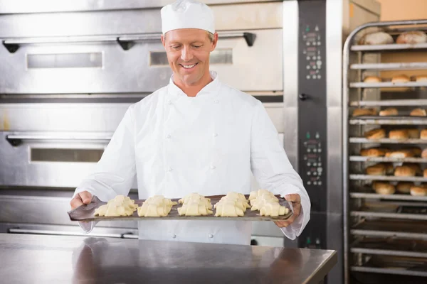 Baker holding tray of raw dough — Stock Photo, Image