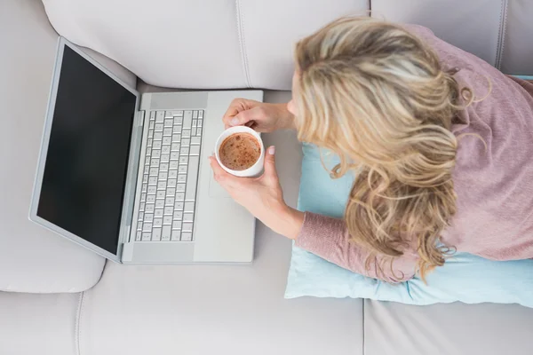 Loira usando laptop enquanto bebe café — Fotografia de Stock