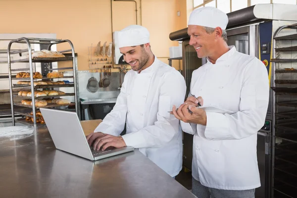 Lächelnde Bäcker arbeiten gemeinsam am Laptop — Stockfoto