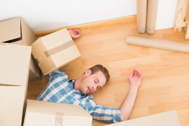 Man lying under fallen boxes clipart