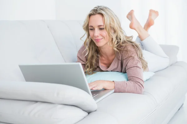 Bionda sdraiata sul divano con laptop — Foto Stock