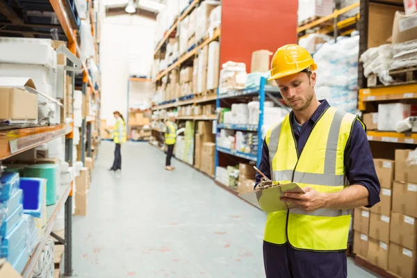 Focused warehouse worker with clipboard — Stock fotografie