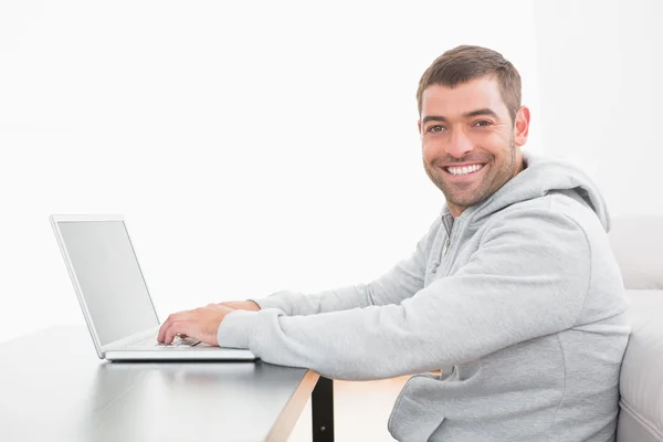 Uomo sorridente che usa il computer portatile a un tavolo — Foto Stock