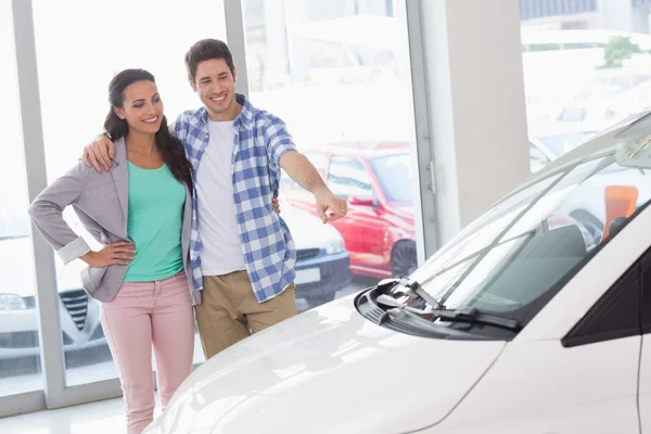 Smiling couple pointing a car — Stock Photo, Image