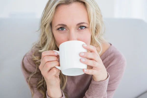 Blondine auf Couch trinkt Heißgetränk — Stockfoto