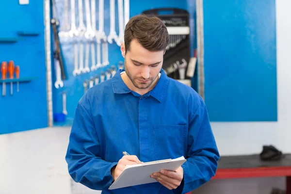 Mechanic writing on a clipboard — Stock Photo, Image