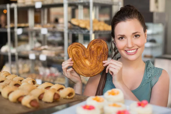 Morena sosteniendo corazón forma pastelería — Foto de Stock