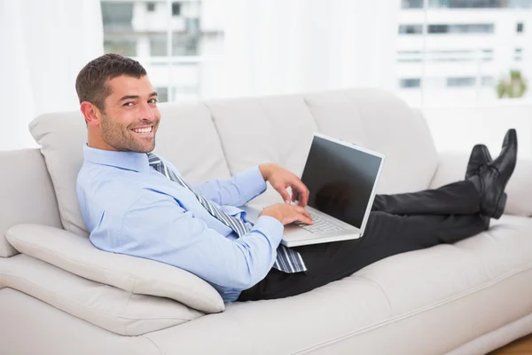 Relaxante empresário em um sofá com um laptop — Fotografia de Stock