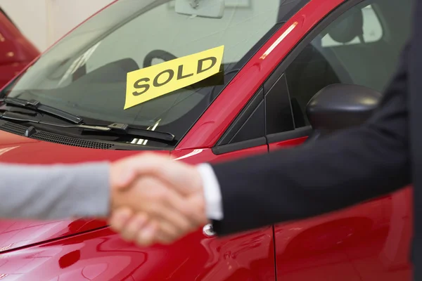 Pessoas apertando as mãos na frente do carro vendido — Fotografia de Stock