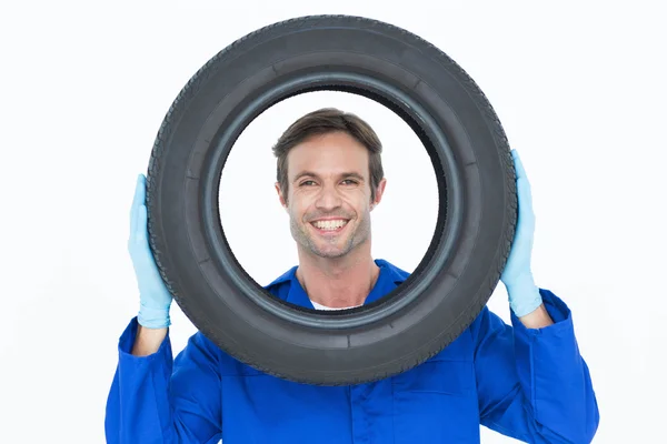 Confident mechanic looking through tire — Stock Photo, Image