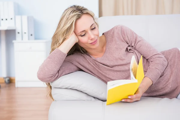 Entspannte Blondine liegt auf Couch beim Lesen — Stockfoto