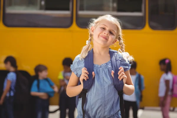 Alunos bonitos sorrindo para a câmera pelo ônibus escolar — Fotografia de Stock