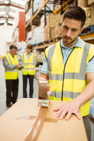 Magazijn werknemer afdichten van kartonnen dozen voor verzending — Stockfoto