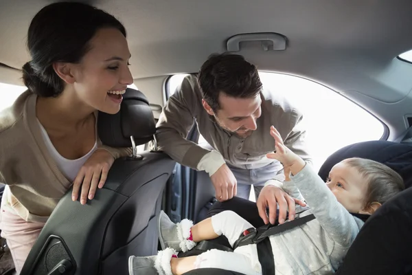 Родители закрепляют ребенка в автомобильном кресле — стоковое фото
