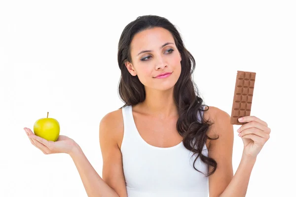 Brünette entscheidet sich zwischen Apfel und Schokolade — Stockfoto