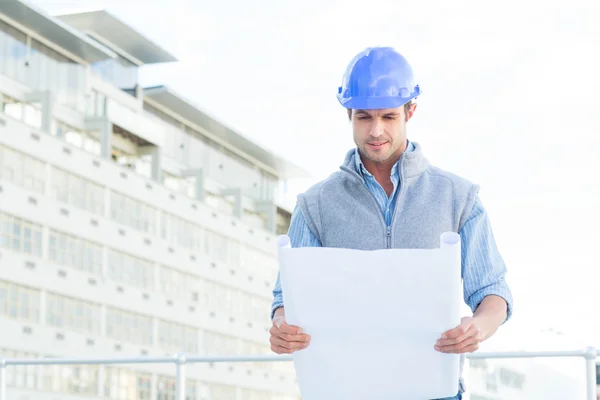 Architect reading blueprint outside building — Stock Photo, Image