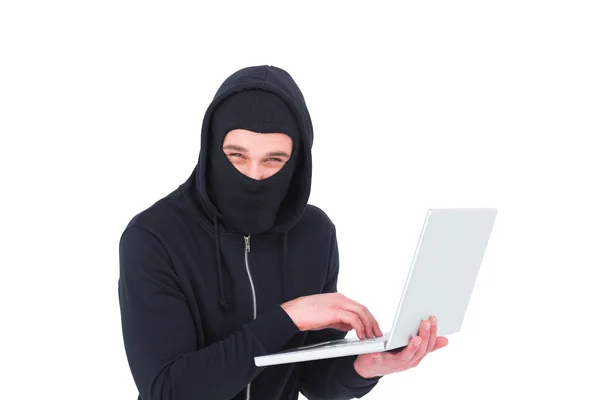 Hacker in balaclava using laptop to steal identity — Stock Photo, Image