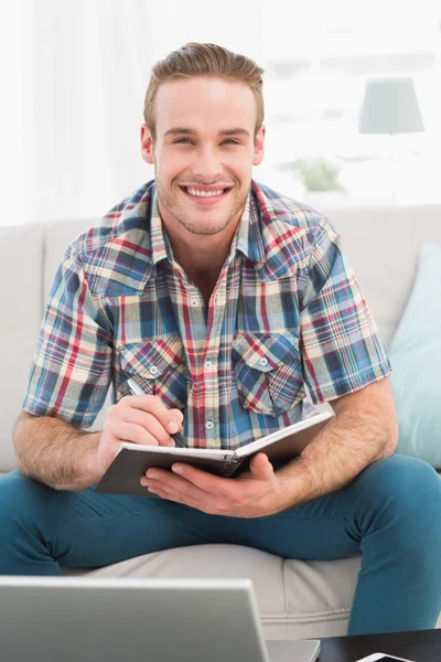 Glimlachende man op een laptop met notebook — Stockfoto