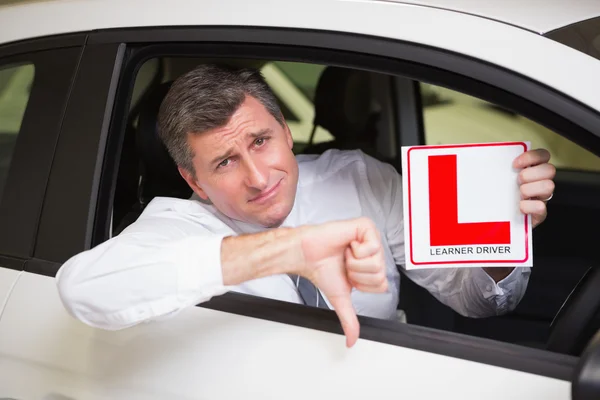 Hombre haciendo gestos con los pulgares hacia abajo sosteniendo una señal de conductor aprendiz — Foto de Stock
