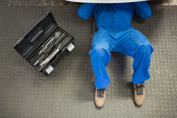 Mecánico mintiendo y trabajando bajo el coche — Foto de Stock