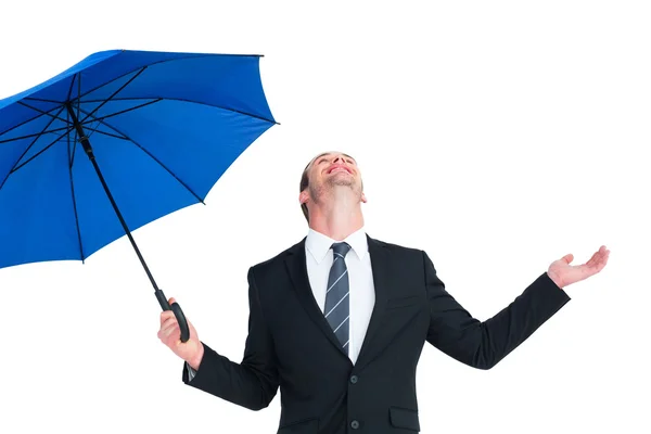 Happy businessman holding blue umbrella and looking up — Stock Photo, Image