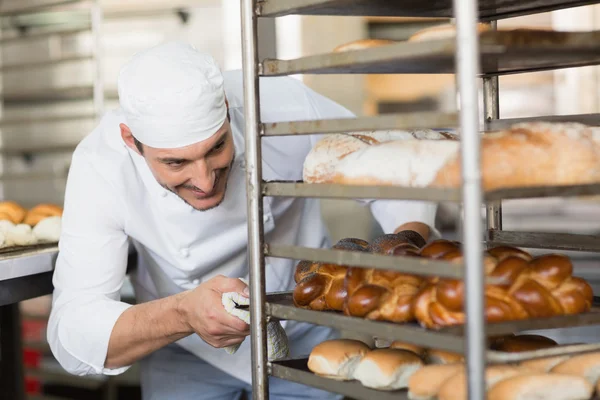 Panadero sonriente empujando bandeja de pan —  Fotos de Stock