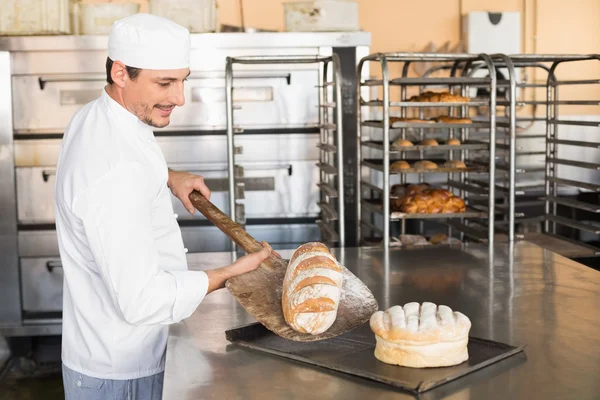 Happy baker taking out fresh loaf — Stock Photo, Image