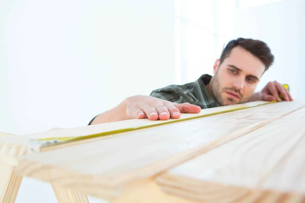 Worker measuring wooden plank — Stock Photo, Image