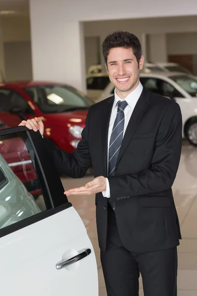 Χαμογελώντας επιχειρηματίας δείχνει ένα αυτοκίνητο προς πώληση — Φωτογραφία Αρχείου