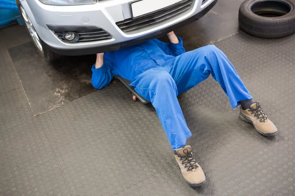 Mechaniker liegt und arbeitet unter Auto — Stockfoto