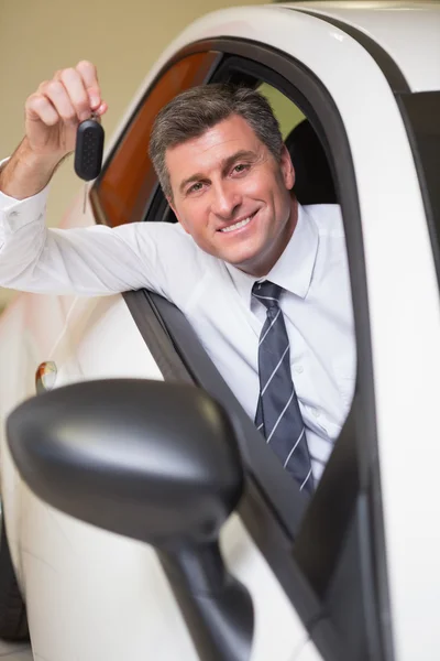 Un homme souriant tenant une clé de voiture assise dans sa voiture — Photo