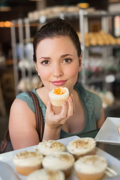 Bonita morena oliendo un cupcake —  Fotos de Stock