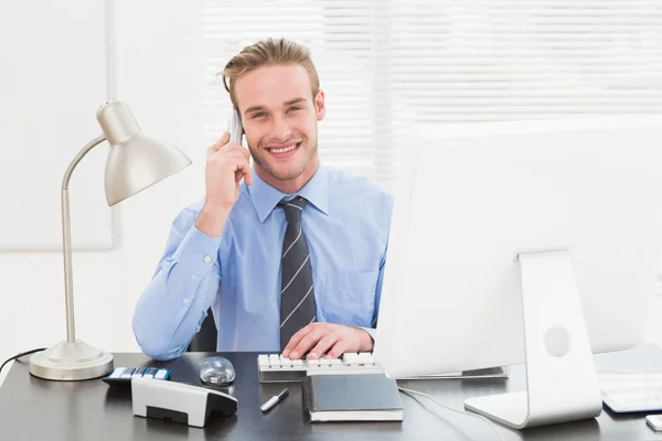 Lächelnder Geschäftsmann beim Arbeiten und Telefonieren — Stockfoto