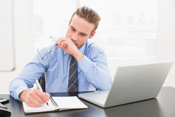 Empresário segurando óculos e tomando notas — Fotografia de Stock