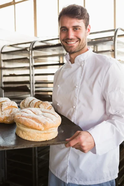 Happy baker showing tray with bread — Stock Photo, Image