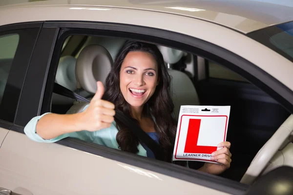 Frau gestikuliert mit erhobenem Daumen und hält Autofahrerschild hoch — Stockfoto