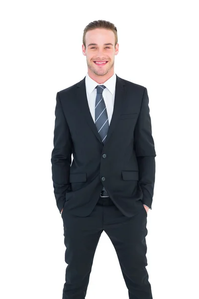 Biznesmen uśmiechający się w garnitur z rękami w kieszeni pozowanie — Zdjęcie stockowe