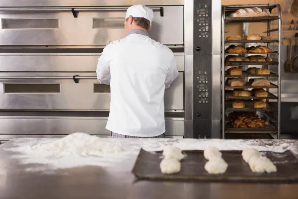 Baker opening oven to put dough in — Stock Photo, Image