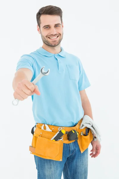 Sonriente trabajador de la construcción sosteniendo la llave inglesa — Foto de Stock