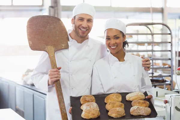 Bakkers lachend met dienbladen van broden — Stockfoto