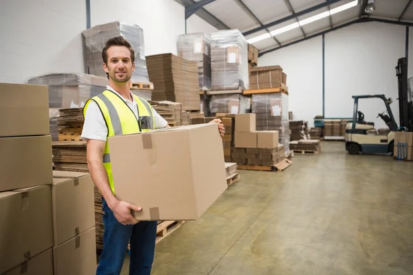 Worker carrying box in warehouse — Stock Photo, Image