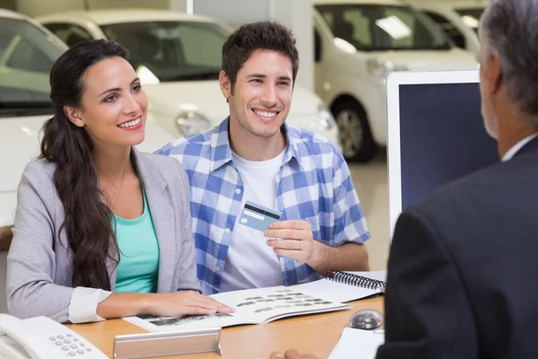 Couple tenant la carte de crédit pour acheter une voiture — Photo