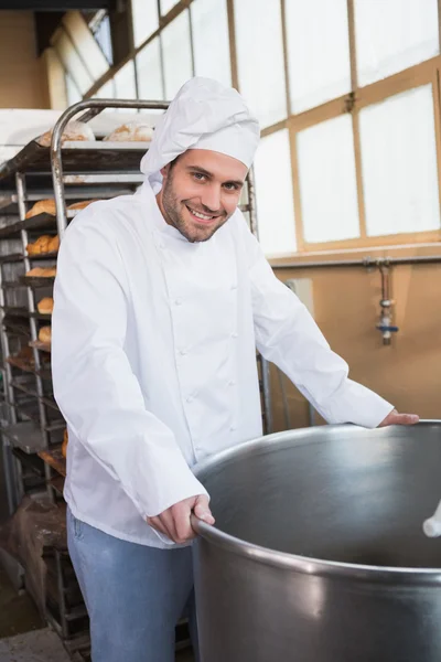 Leende baker lutande på industriella mixer — Stockfoto