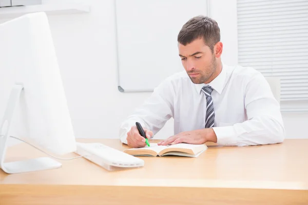 Uomo d'affari seduto alla scrivania a leggere un libro — Foto Stock