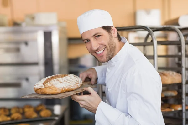Assadeira sorridente cheirando pão fresco — Fotografia de Stock