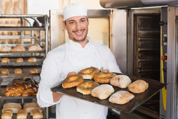 Assadeira feliz mostrando bandeja de pão fresco — Fotografia de Stock