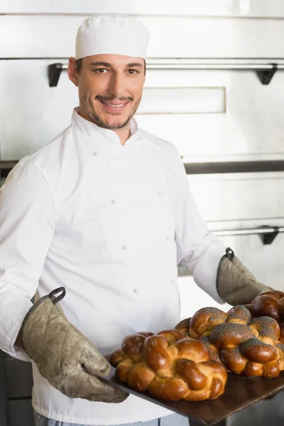 Happy baker showing tray of fresh bread — Stock Photo, Image