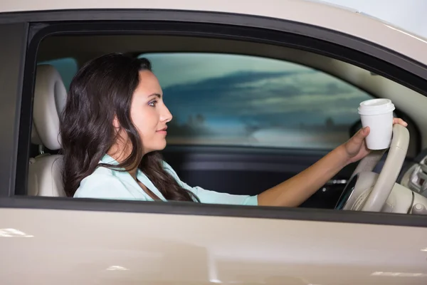 Lachende vrouw auto rijden terwijl het drinken van koffie — Stockfoto