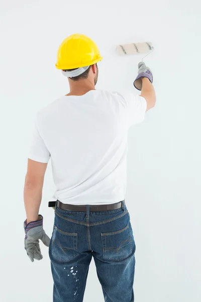 Hombre usando hardhat mientras usa rodillo de pintura —  Fotos de Stock