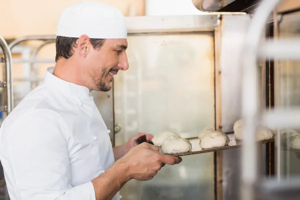 Assadeira sorrindo colocando massa no forno — Fotografia de Stock